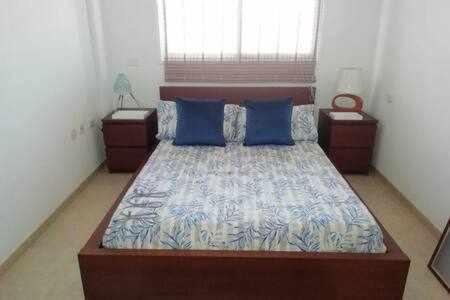a bedroom with a large bed with blue pillows at Casas Galloway - Puertito Güímar. Sol y comodidad. in Puertito de Güímar