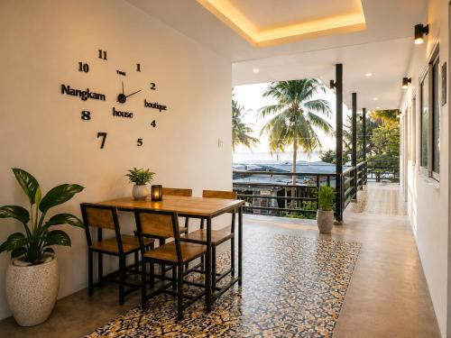 a dining room with a table and a clock on the wall at Nangkam Boutique Donsak in Ban Pheng Krong