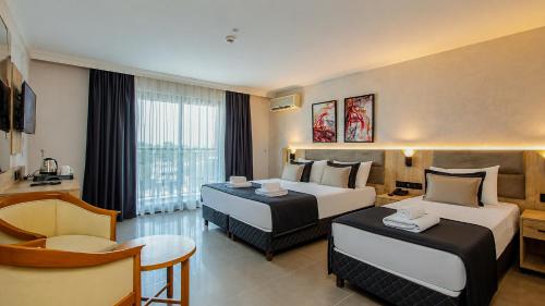 a hotel room with two beds and a chair at World Star Beach Resort & Spa in Alanya