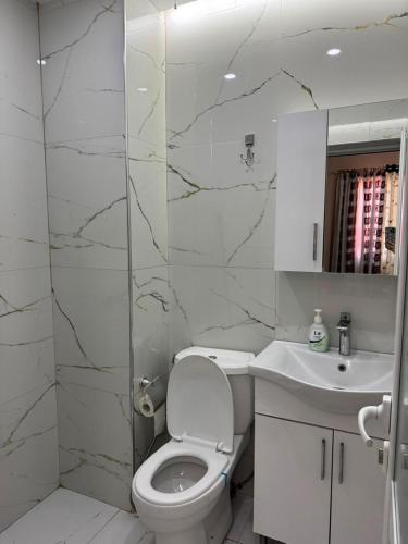 a white bathroom with a toilet and a sink at Vila Topi in Vlorë