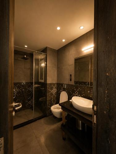a bathroom with a toilet and a sink and a shower at TGC Resort And Hotel Arpora in Calangute