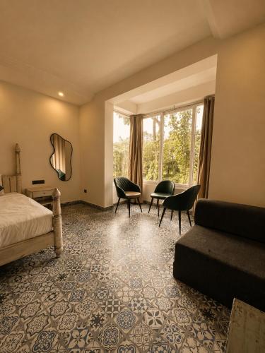 a bedroom with a bed and chairs and a window at TGC Resort And Hotel Arpora in Calangute
