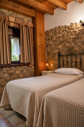 a bedroom with two beds and a stone wall at Posada La Llosa de Viveda - Adults Only in Santillana del Mar