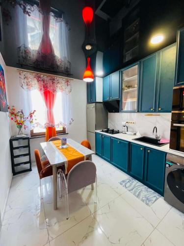 a kitchen with blue cabinets and a table and chairs at Appartaments Anna Kostava in Kobuleti
