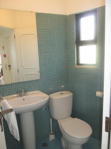 a bathroom with a white toilet and a sink at Casa Vila Verde in Quarteira
