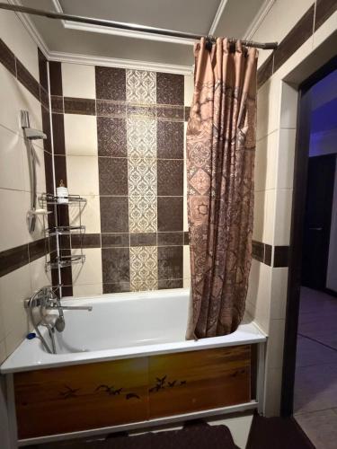 a bathroom with a tub and a shower curtain at 3 комнатные апартаменты in Karagandy