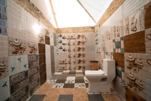 a bathroom with a toilet and a checkered floor at Rumis Desert Camp in Jaisalmer