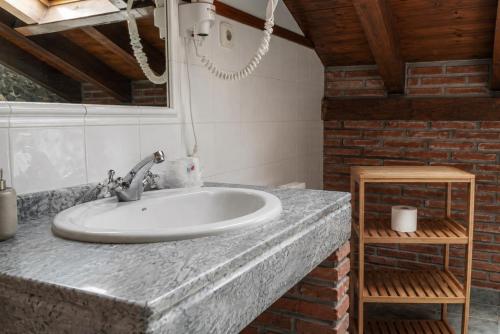a bathroom with a sink and a brick wall at Posada La Llosa de Viveda - Adults Only in Santillana del Mar