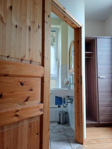 a bathroom with a wooden door and a sink at Hotel Restaurant Kommodich in Kellinghusen