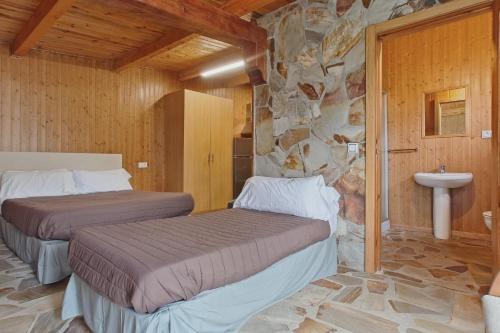 a bedroom with two beds and a stone wall at Vivienda Jardin in Monforte de Lemos