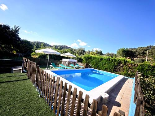a swimming pool in a yard with a wooden fence at El Andén del Hueznar in Constantina