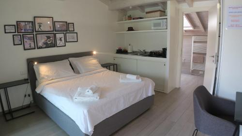 a bedroom with a bed with white sheets and a kitchen at i laghi di Como in Erba