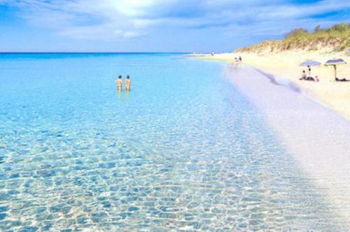 two people standing in the water on a beach at Villa Nepole in Torre Vado