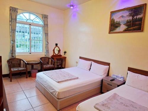 a bedroom with two beds and a table and a window at Taitung Moon House in Luye