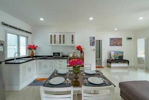 a kitchen and living room with a table and chairs at Chalong - 2 Bedroom Hideaway Private Pool Villa - Phuket in Chalong