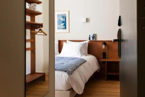 a bedroom with a bed with white sheets and a wooden headboard at Alfred Hotels Paris Gare du Nord- Hôtel Rénové in Paris