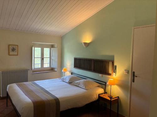 a bedroom with a large white bed with two lamps at Hotel Le Moulin du Château in Saint-Laurent-du-Verdon