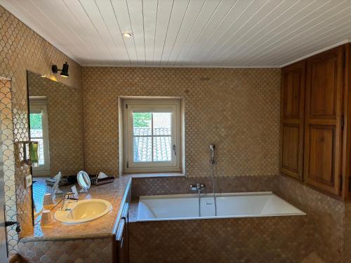 a bathroom with a large tub and a sink at Hotel Le Moulin du Château in Saint-Laurent-du-Verdon