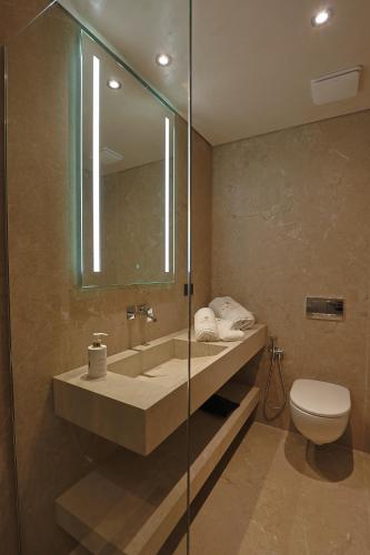 a bathroom with a sink and a toilet and a mirror at Hotel Camelot By Artur in Ksamil