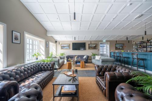 a living room with leather couches and a bar at Hotel Stafholt in Varmaland