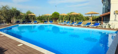 a large blue swimming pool with chairs and umbrellas at Achillion Hotel in Skala Potamias