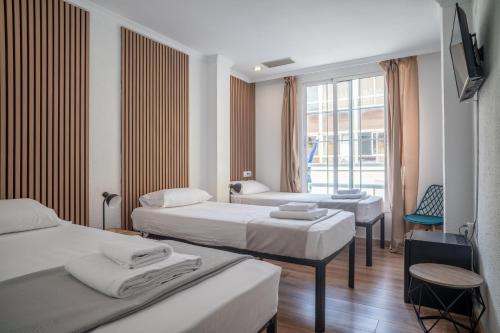 a hotel room with three beds and a window at Ella Torremolinos Centro in Torremolinos