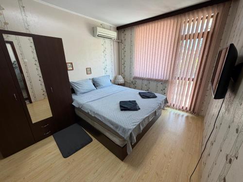 a bedroom with a bed with blue sheets and a television at Izgrev Sarafovo in Burgas