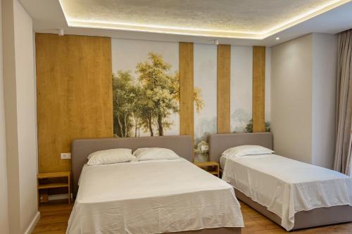 a bedroom with two beds and a painting on the wall at Zena Hotel Durres in Durrës