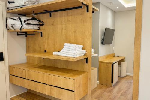 a room with wooden shelves and a television and towels at Zena Hotel Durres in Durrës