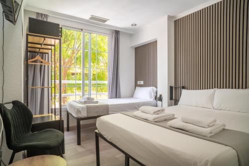a bedroom with two beds and a chair and a window at Ella Torremolinos Centro in Torremolinos