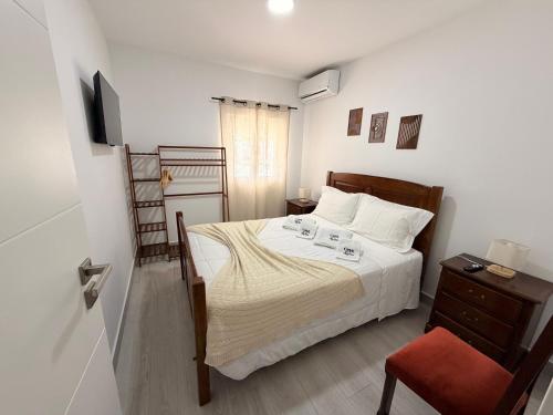 a small bedroom with a bed and a chair at Casa dos Avós in Santa Eulália