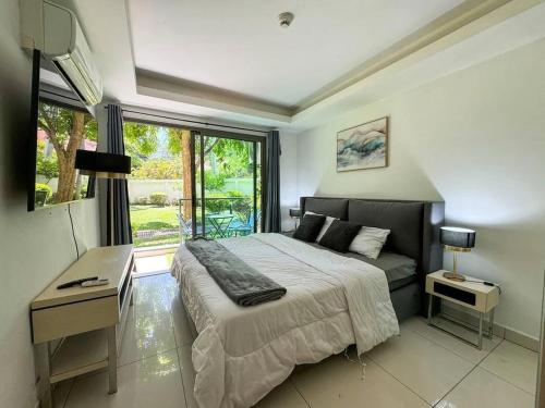 a bedroom with a bed and a desk and a window at Pattaya Laguna Beach Resort 2 in Nong Prue