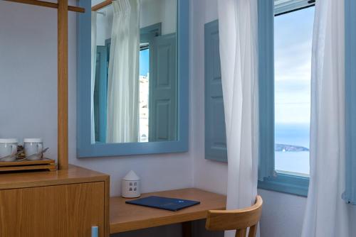 a room with a desk with a mirror and a window at Helestia Hotel, Caldera Santorini in Firostefani