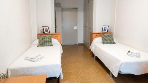a room with two beds with white sheets at Residencia Universitaria Resa Sant Jordi in Tarragona