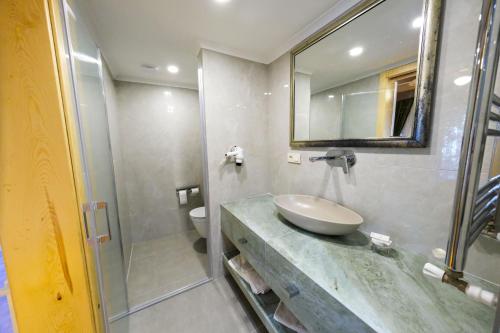 a bathroom with a sink and a toilet and a mirror at Palace Hotel Olive Odore in Küçükkuyu