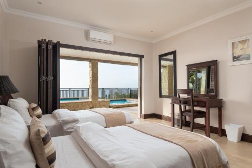 a bedroom with two beds and a desk and a balcony at Stella Road 24 in Ballito