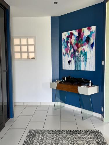 a blue room with a table and a painting on the wall at Chez Marianne in Wailly