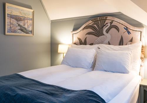 a bedroom with a white bed with a large headboard at Hotel Breiseth in Lillehammer