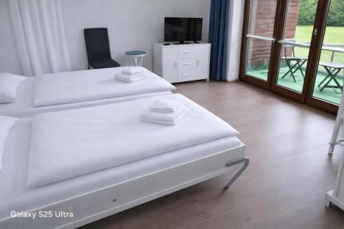 two white beds in a room with a tv at PEMATRA Ferienwohnungen Ostseestrasse 2 in Travemünde