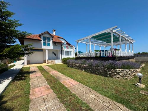 a white house with a porch and a yard at Guest house FantasY in Tyulenovo
