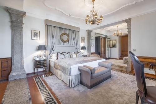 a bedroom with a bed and a chair and a chandelier at Hotel Schloss Mönchstein in Salzburg