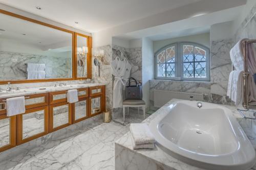 a bathroom with a large tub and a large mirror at Hotel Schloss Mönchstein in Salzburg