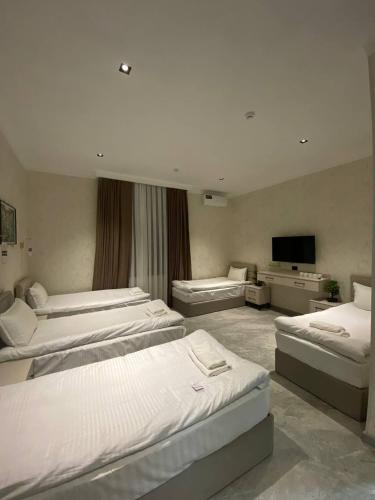 a room with four beds and a flat screen tv at Pandora Hotel in Samarkand