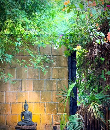 a stone wall with a statue in front of it at Alcove Bungalow in Hinkong
