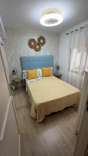 a bedroom with a bed with a blue headboard and yellow pillows at CORNELIAS HOME 1A between LAS VISTAS & LOS CRISTIANOS BEACH in Los Cristianos