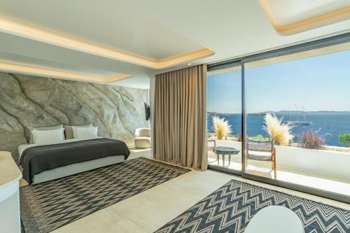 a bedroom with a bed and a large window at Tagoo Hills in Mikonos