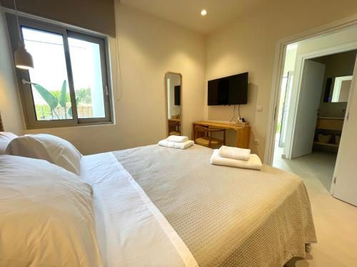 a bedroom with a white bed with two towels on it at MIRA MARE - Apartments 1 & 8 in Stavros