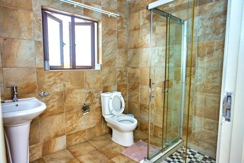 a bathroom with a toilet and a glass shower at Potato Suites n Spa in Gaborone
