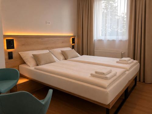 a bedroom with a large white bed with a window at Pension Klatovy in Klatovy