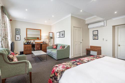 a bedroom with a bed and two chairs and a desk at The White Hart Hotel, Boston, Lincolnshire - The Coaching Inn Group in Boston